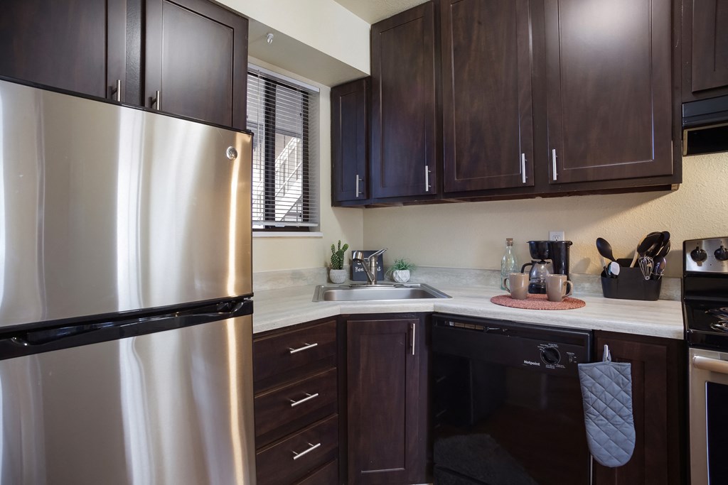 Kitchen with stainless steel appliances and dark wood cabinets  at Governor's Park, Fort Collins, 80525