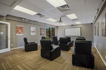 Screening room filled with black chairs and a white screen at Mountain Run Apartments, New Mexico, 87111