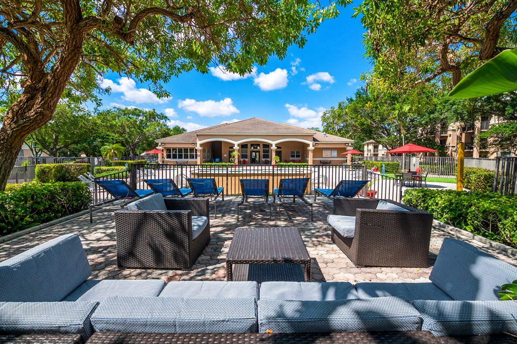 a patio with chairs and tables and a house in the background at Pembroke Pines Landings, Pembroke Pines, FL, 33025