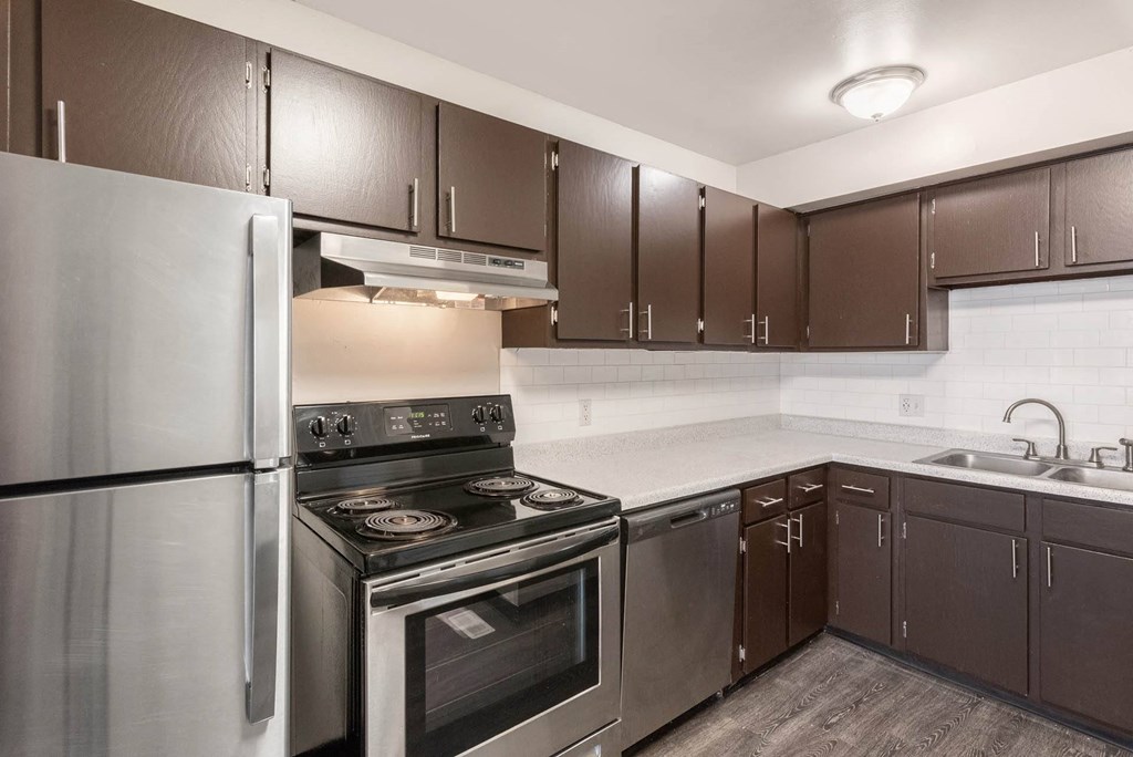 a kitchen with a stove top oven next to a refrigerator at Aspen Townhomes, Colorado Springs, CO