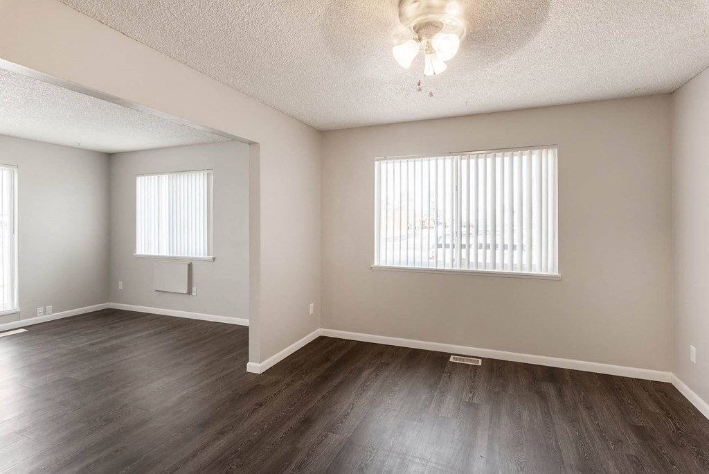 a bedroom with hardwood floors and two windows at Aspen Townhomes, Colorado Springs, 80909