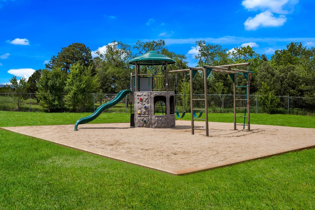 a sandpit with a jungle gym and slide in the middle of a grassy park at Broadmoor Springs, Colorado Springs, CO, 80906