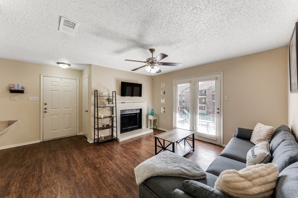 a living room with a couch and a ceiling fan and a fireplace at The Glen Apartments, Texas