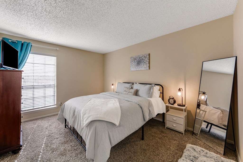 Bedroom a bedroom with a bed and a dresser and a mirror at The Glen Apartments, Texas, 75067