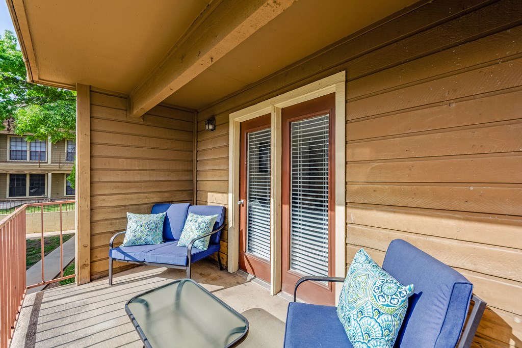 a covered porch with chairs and a table at The Glen Apartments, Texas