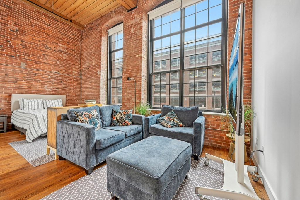 a living room with two couches and a large window at Riverwalk Apartments, Lawrence, MA