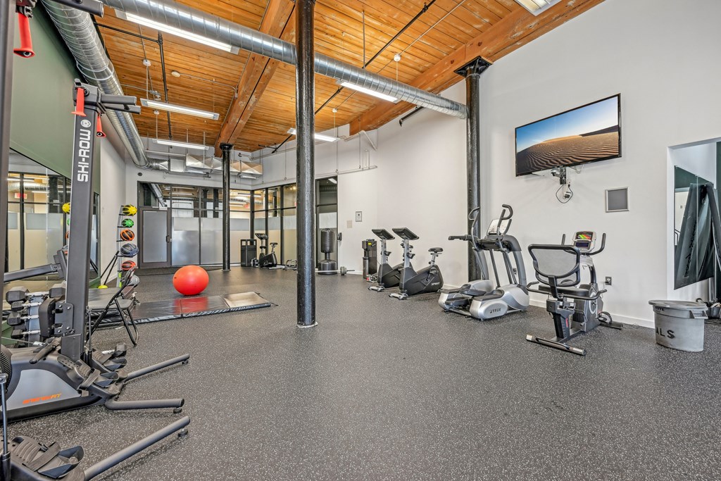 a gym with cardio equipment and weights on the floor and a tv at Riverwalk Apartments, Lawrence, MA