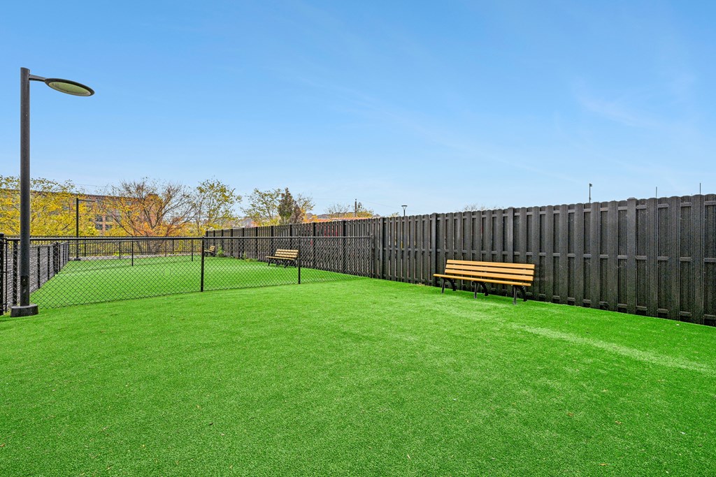 a yard with a tennis court and benches at Riverwalk Apartments, Lawrence, MA
