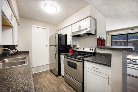 Kitchen with white cabinetry and black appliances at Windmill Apartments, Colorado, 80916