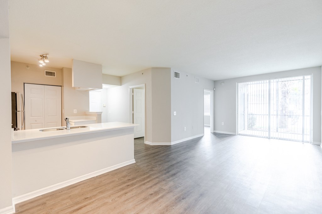 a kitchen and living room with hardwood floors and a sliding glass door to a balcony at Heritage Bay, Jensen Beach, FL