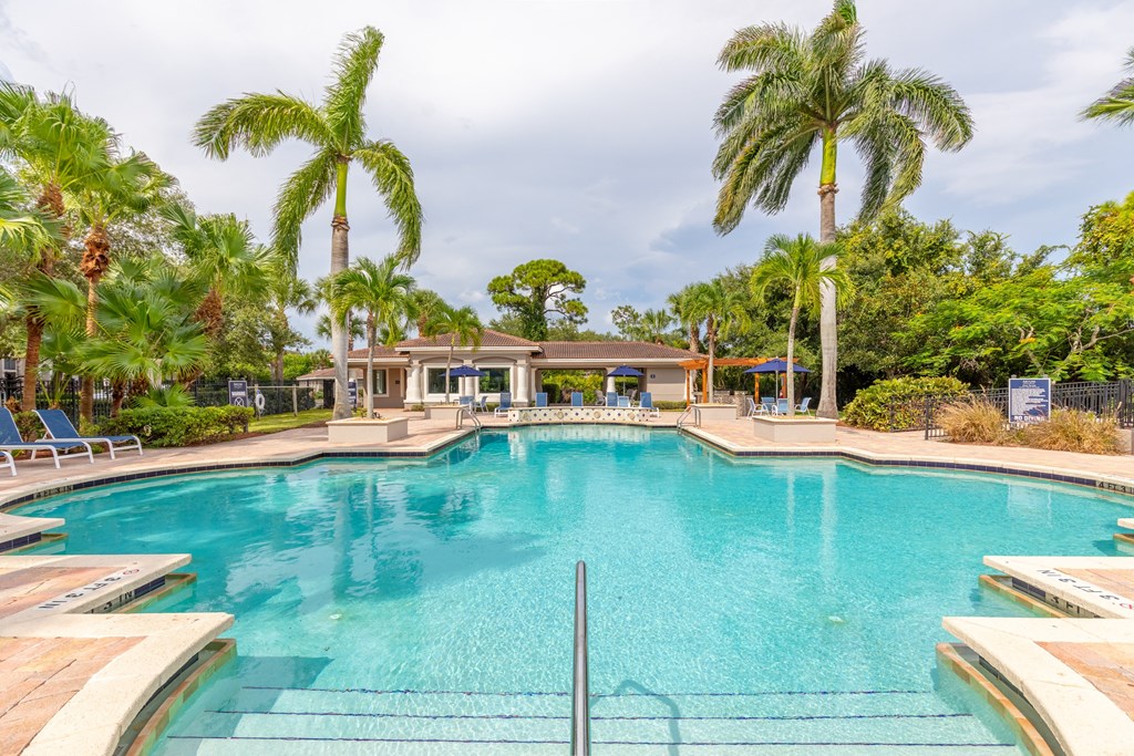a large swimming pool with palm trees in the background at Heritage Bay, Jensen Beach, FL