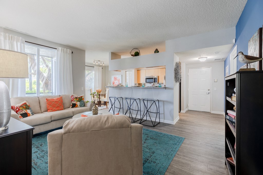 a living room with a kitchen in the background and a couch and chair in the foreground at Heritage Bay, Jensen Beach, FL 34957