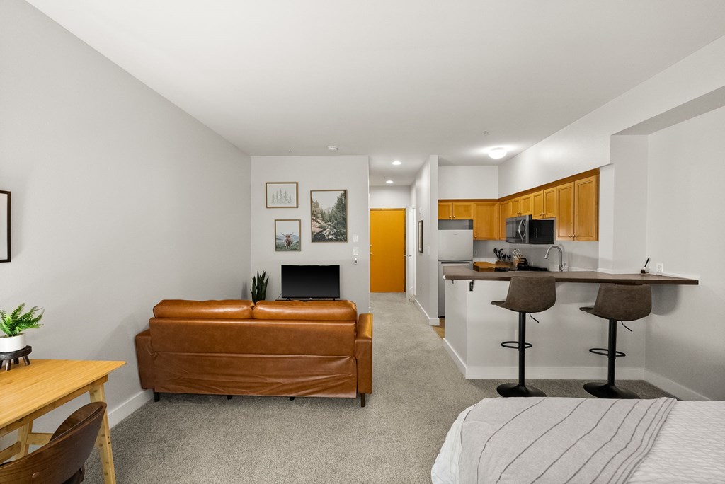A living room with a brown leather couch and a fireplace.