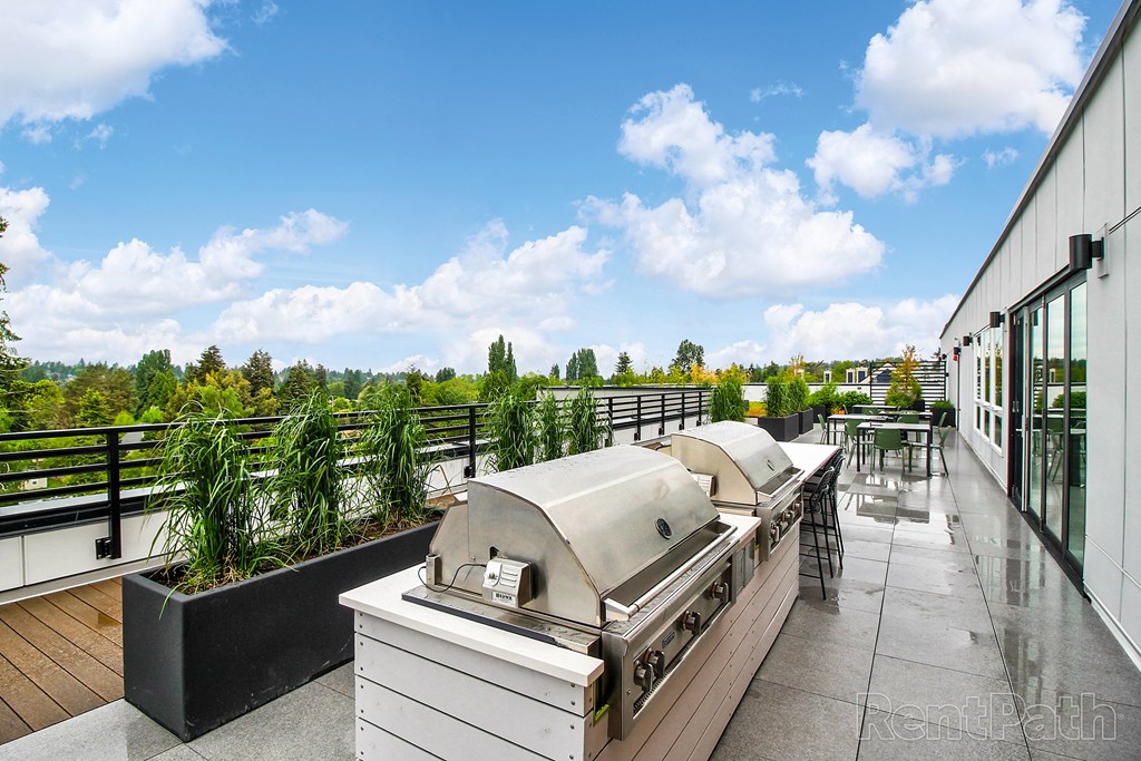 a roof deck with a barbecue grill and a view of the city