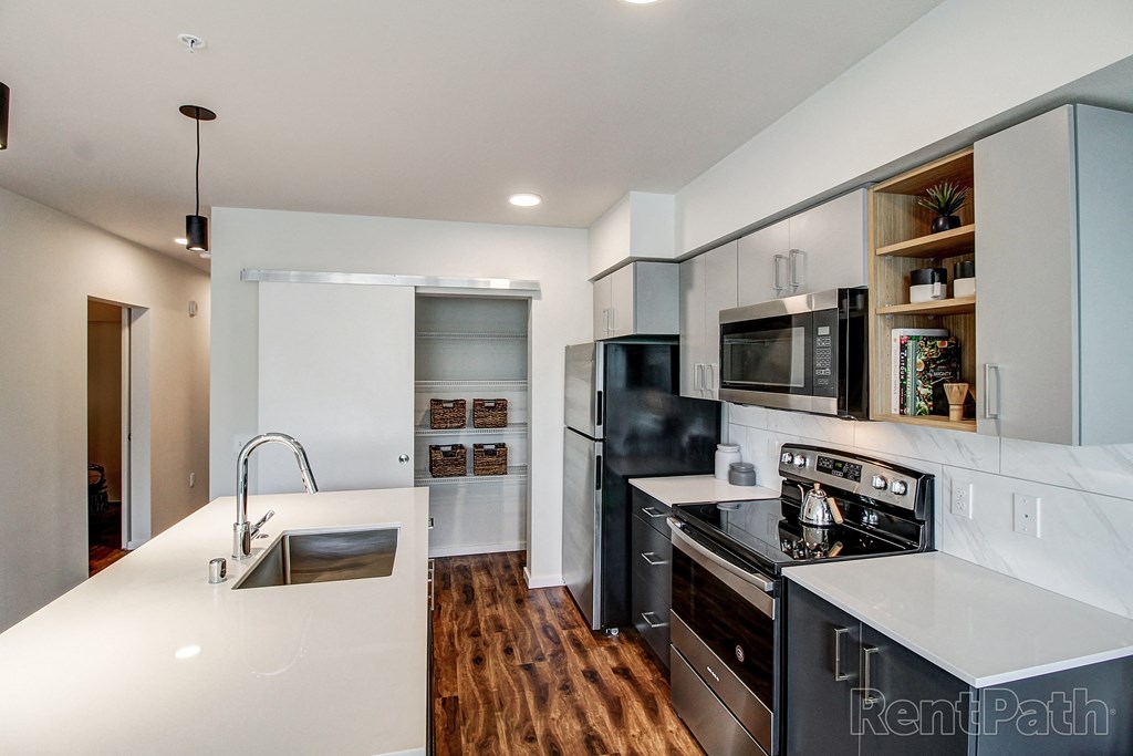 a white kitchen with black appliances and white counter tops