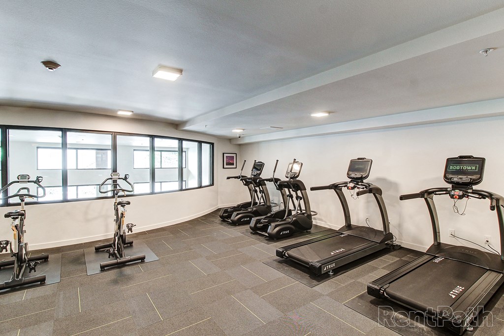 a gym with various exercise machines and a large window