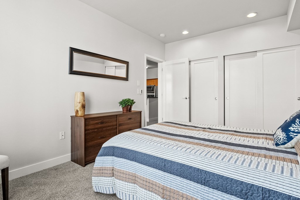 A bedroom with a bed, dresser, and mirror.
