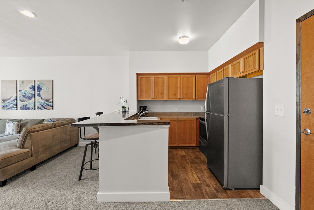 A kitchen with a refrigerator, a table, and a couch.