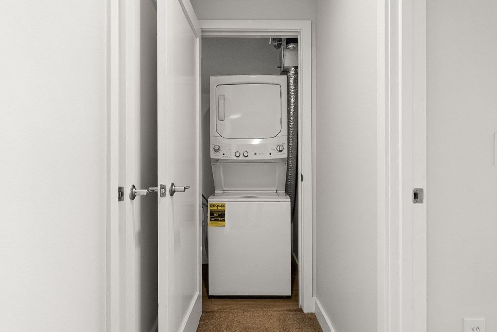 A white dryer is in a small white room.