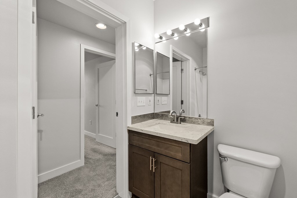 A bathroom with a white toilet, sink, and mirror.