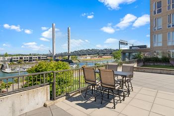 A patio with chairs and a table overlooking a river.
