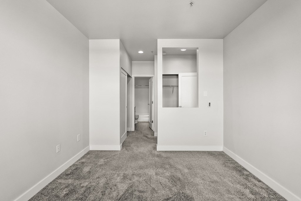 A spacious, empty room with carpeted flooring and white walls.