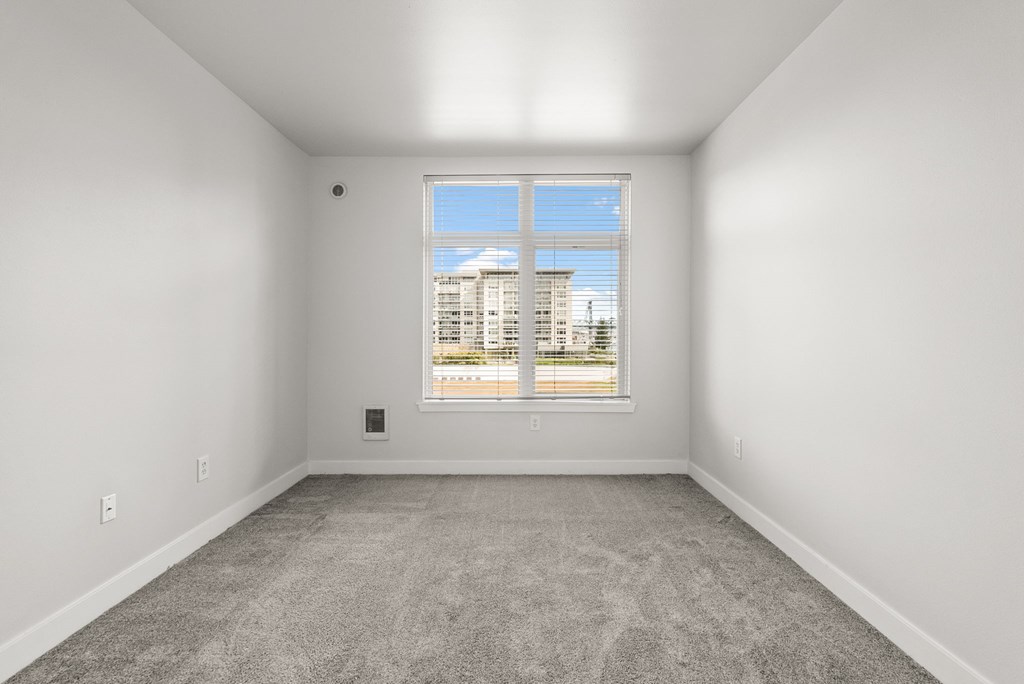 A large empty room with a window overlooking a cityscape.