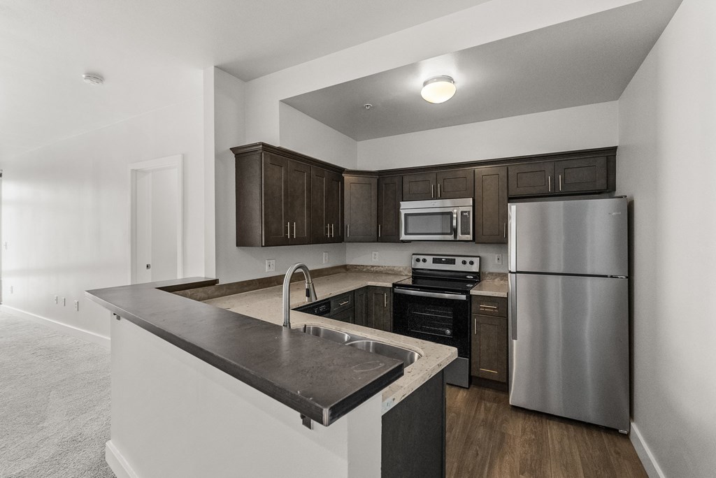 A modern kitchen with a stainless steel refrigerator and dark brown cabinets.