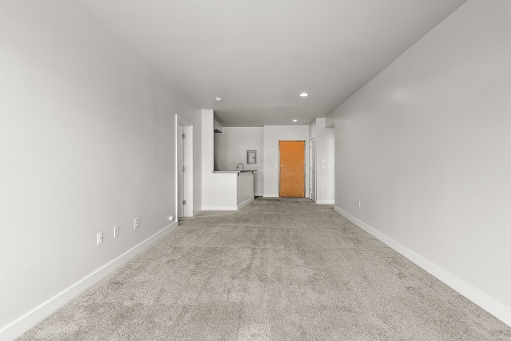 A long, empty hallway with a carpeted floor and white walls.