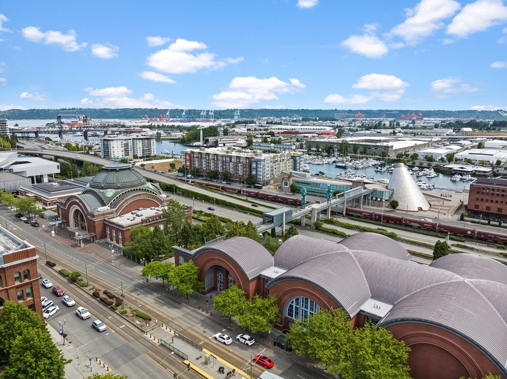 A city street with a large building with a curved roof in the foreground.