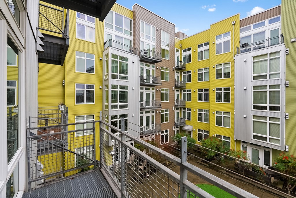 A view of a balcony with a yellow building in the background.
