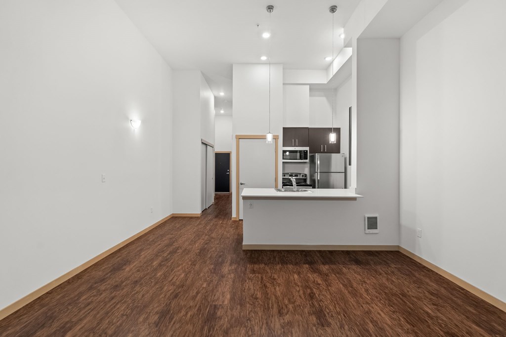 A kitchen with white walls and wooden floors.