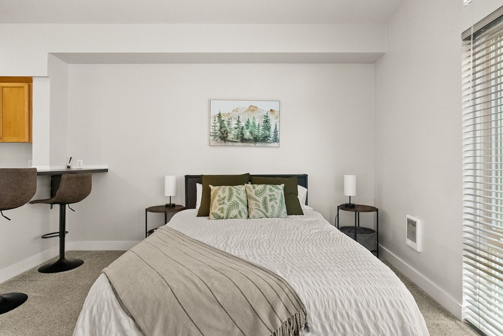 A bedroom with a large bed and a painting on the wall.