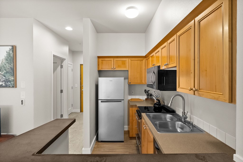 A kitchen with wooden cabinets and a stainless steel refrigerator.