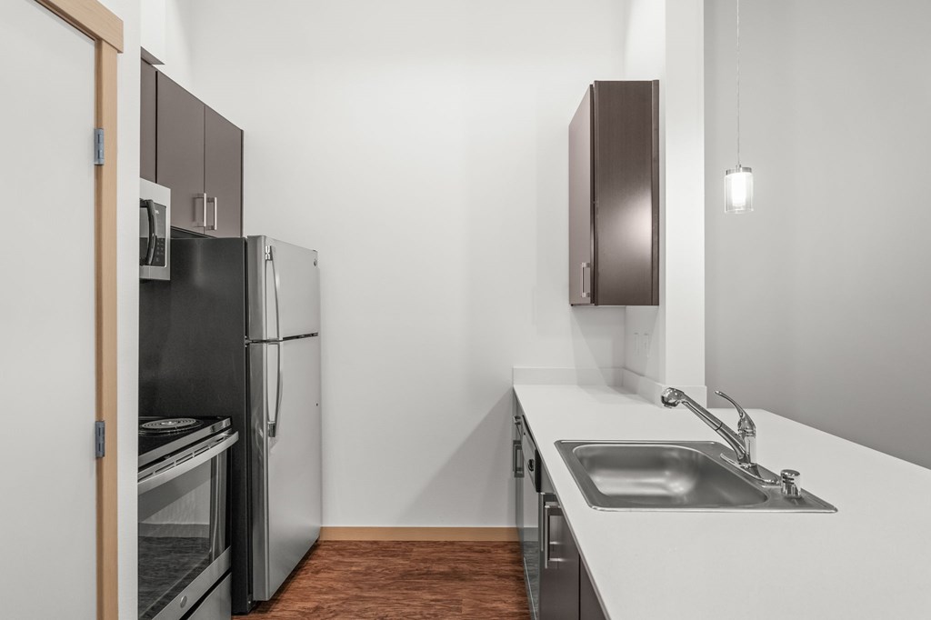 A kitchen with a white counter top and a black fridge.