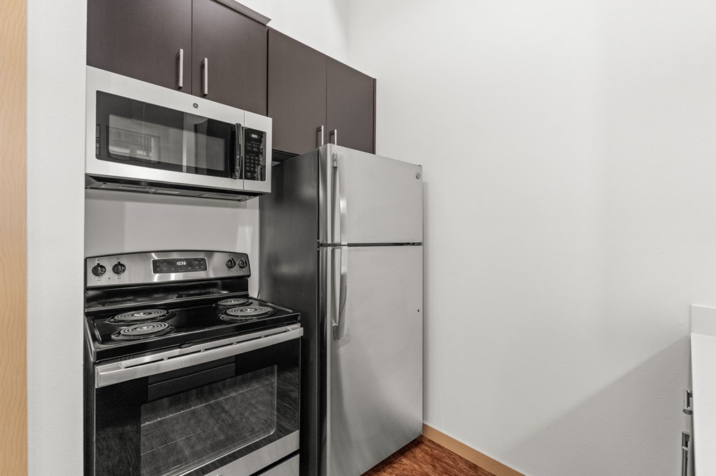 A kitchen with a stove, oven, microwave and refrigerator.