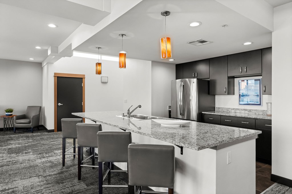 A modern kitchen with a bar area and grey chairs.