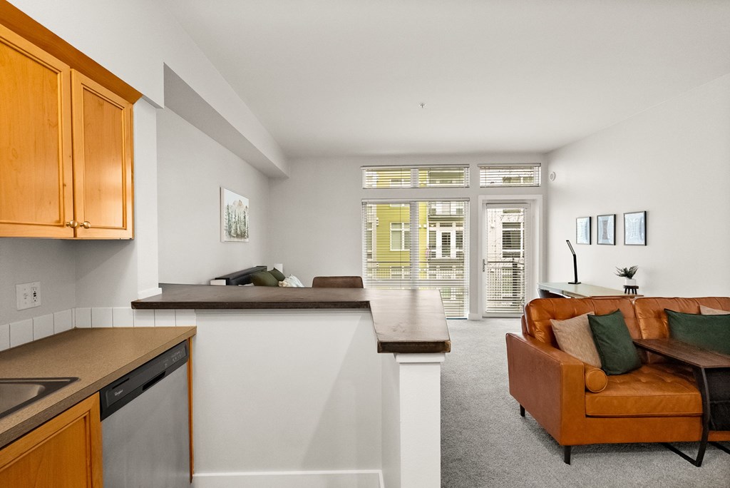 A kitchen with a brown couch and a window.