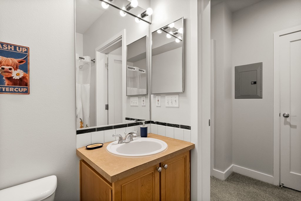 A bathroom with a wooden vanity and a poster on the wall.