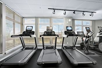 Three treadmills are lined up in a row in a bright room.