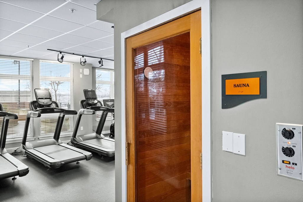 A gym with treadmills and a sign that says Sauna.