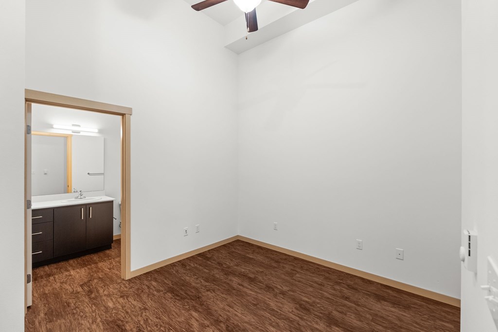 A room with a brown floor and a ceiling fan.