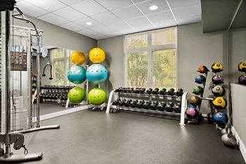 A gym with a variety of equipment including dumbbells and exercise balls.