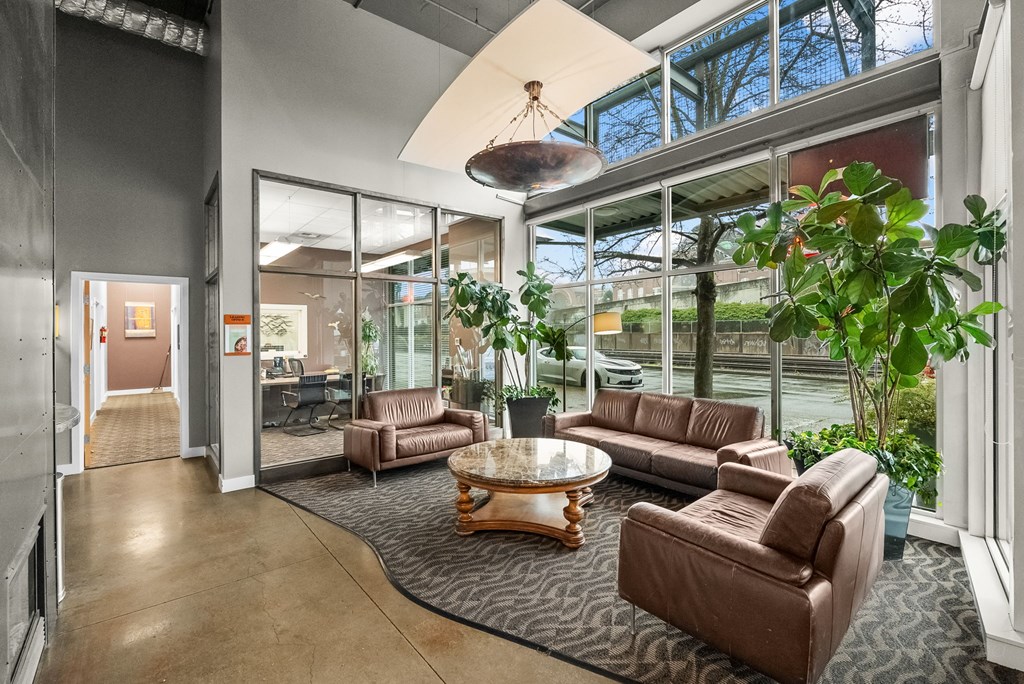 A living room with a brown leather couch and a glass table.