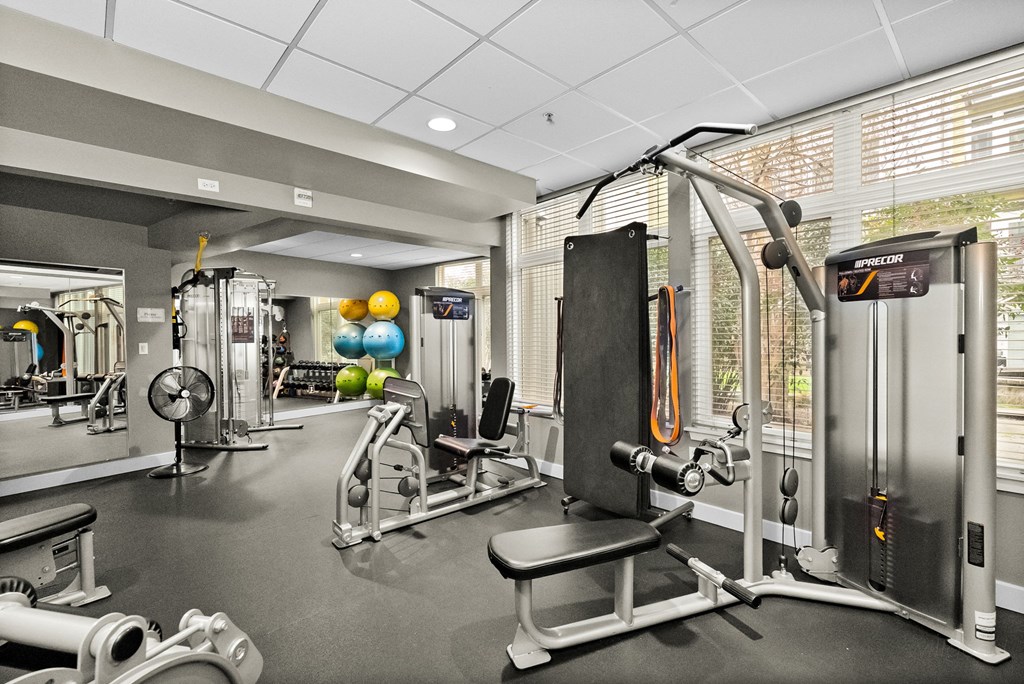 A gym with a variety of equipment including a weight bench, a leg press machine, and a cable machine.