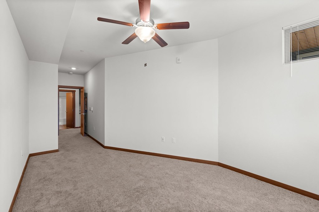 A room with a ceiling fan and carpeted floor.