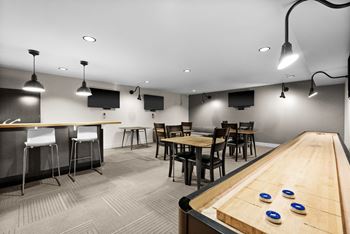 A room with a shuffleboard table and bar area.