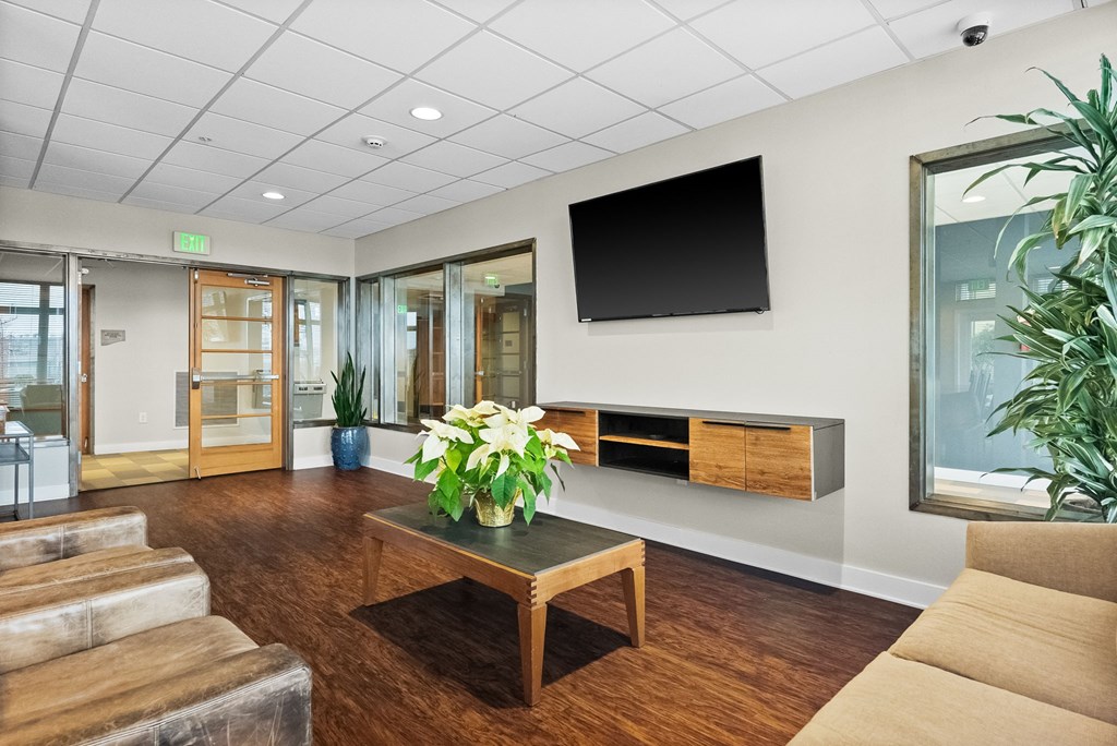 A living room with a wooden floor and a flat screen TV mounted on the wall.