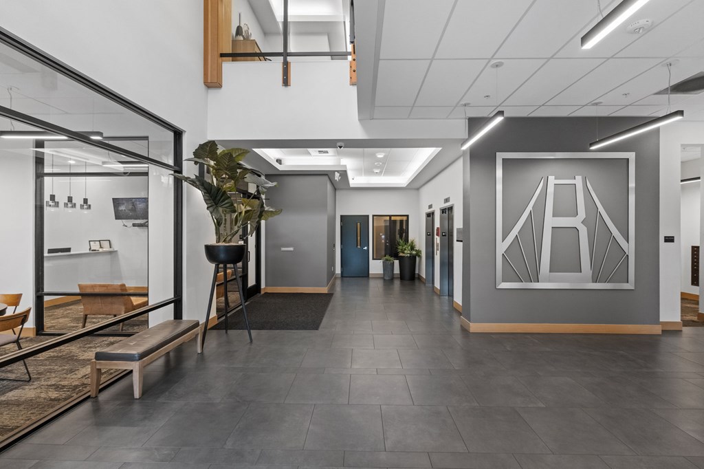A modern office space with a glass wall and a bench.