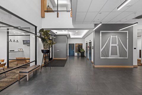 A modern office space with a glass wall and a bench.
